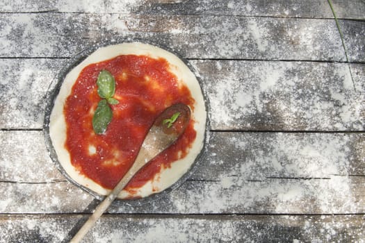 Preparing pizza made with tomato basil and mozzarella 