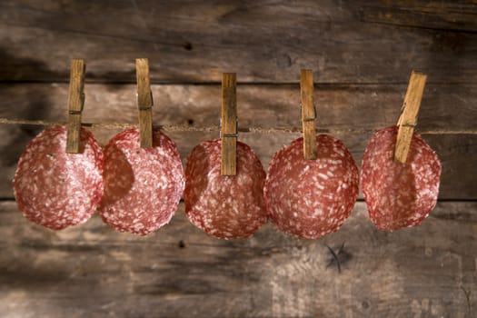 Presentation of slices of salami hanging by a thread