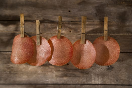 Presentation of slices of salami hanging by a thread