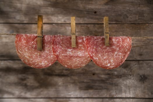 Presentation of slices of salami hanging by a thread