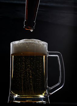 Full beer glass with foam and bottle with drop