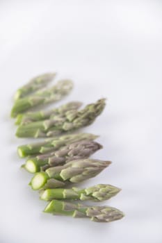 Presentation of raw asparagus spears on a white background
