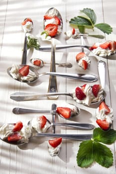 Presentation of the strawberries with cream spoons on various 
