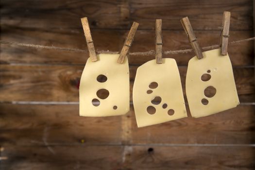 Presentation of slices of Swiss cheese Emmentaler hanging by a thread