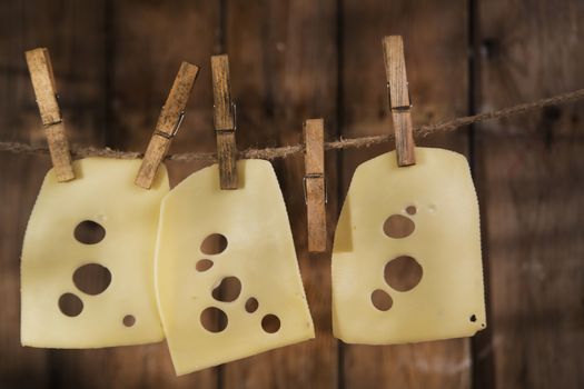 Presentation of slices of Swiss cheese Emmentaler hanging by a thread