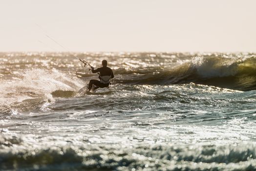 Kitesurfer in action on a beautiful background of spray during the sunset.