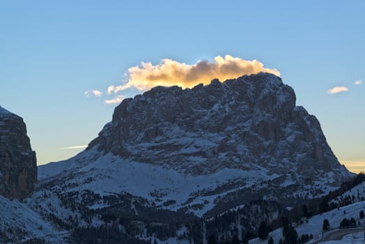 sunlit clouds at sunset over the mountain Sassolungo in winter, Dolomiti