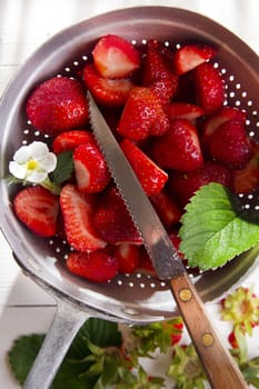 Preparing a fruit salad, strawberries into small pieces. 