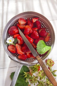 Preparing a fruit salad, strawberries into small pieces. 
