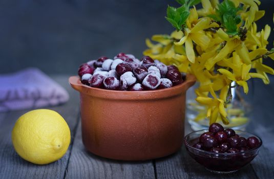 Frozen cherries in a ceramic pot, cherry jam and lemon.Beavertail gray-blue background, rustic style