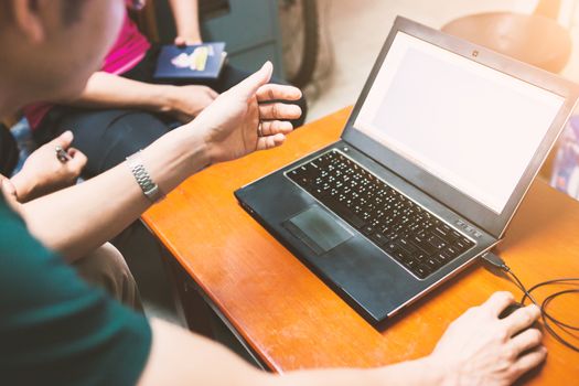 Professional team of talking and looking at a project on laptop at work .