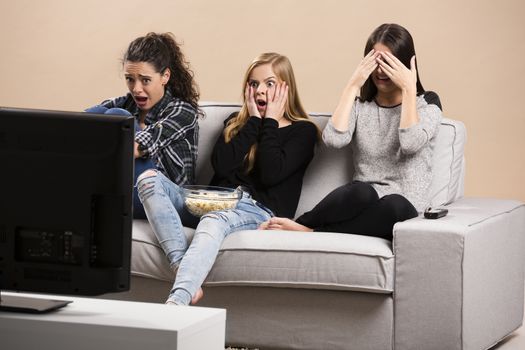 Teenage girls watching horror movie with popcorn