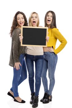 Studio portrait of three teenage girls holding a chalkboard