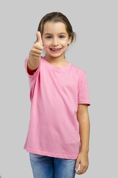 Studio portrait of a beautiful little girl with thumbs up