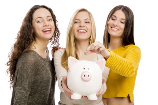 Studio portrait of three teenage girls holding a piggybank