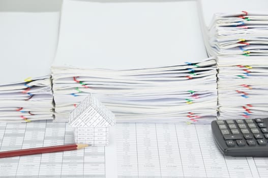 House with brown pencil and calculator on finance account have overload of paperwork with colorful paperclip as background.