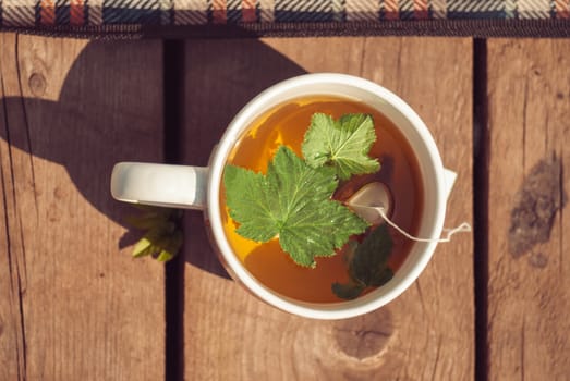 Top view of tea with currant leaf in white cup