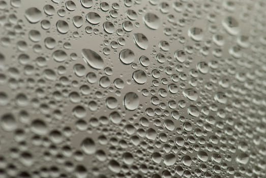 close-up of water drops on the gray background with town reflection.