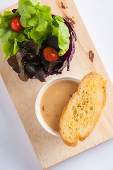 Mushroom soup in ceramic cup with toast and freash vegetables on wood plate. Clean and healthy eating concept food.