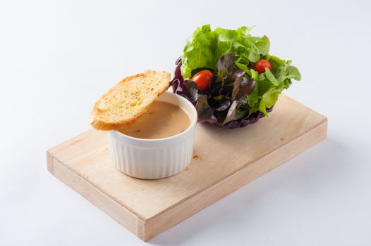Mushroom soup in ceramic cup with toast and freash vegetables on wood plate. Clean and healthy eating concept food.