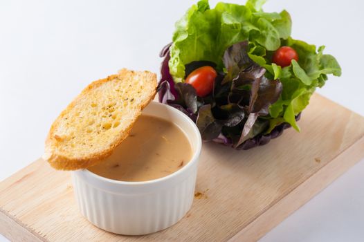 Mushroom soup in ceramic cup with toast and freash vegetables on wood plate. Clean and healthy eating concept food.