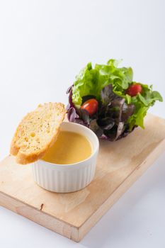 Corn soup in ceramic cup with toast and freash vegetables on wood plate. Clean and healthy eating concept food.