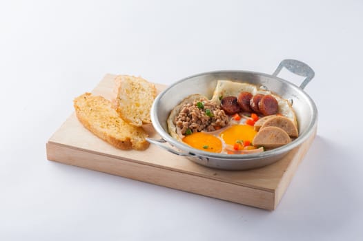 Vietnamese style pan-freid egg with Chinese sausage, minced pork, Vietnamese sausage in metal pan on wood plate with toast
