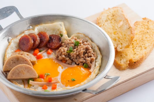Vietnamese style pan-freid egg with Chinese sausage, minced pork, Vietnamese sausage in metal pan on wood plate with toast