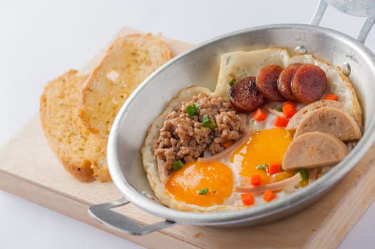 Vietnamese style pan-freid egg with Chinese sausage, minced pork, Vietnamese sausage in metal pan on wood plate with toast