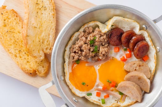 Vietnamese style pan-freid egg with Chinese sausage, minced pork, Vietnamese sausage in metal pan on wood plate with toast