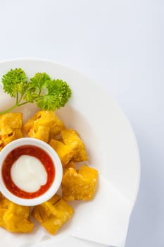 Chinese style deep-fried wonton with sweet and sour sauce in ceramic dish.