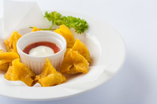 Chinese style deep-fried wonton with sweet and sour sauce in ceramic dish.