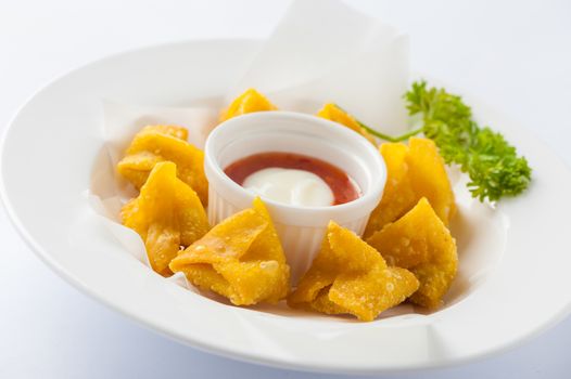 Chinese style deep-fried wonton with sweet and sour sauce in ceramic dish.