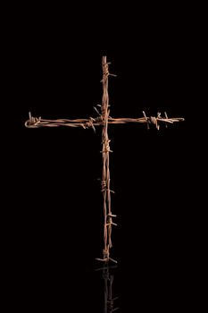 Rusty barbwire cross isolated on black background. Religious war.