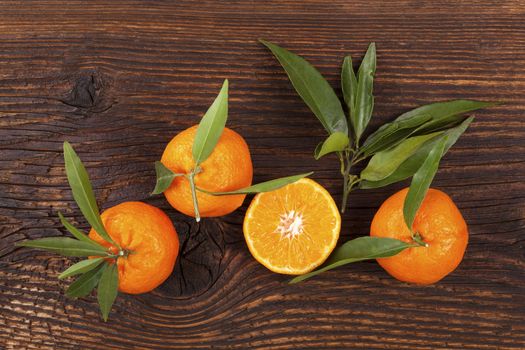 Fresh ripe mandarines with green leaves on wooden table. Organic fresh mandarines, healthy fruit eating. 