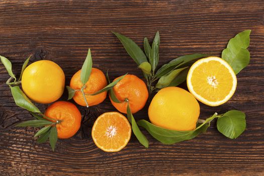 Fresh ripe mandarines with green leaves on wooden table. Organic fresh mandarines, healthy fruit eating. 