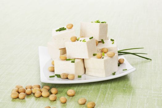Tofu and soybeans on green background. Natural vegan and vegetarian eating. 