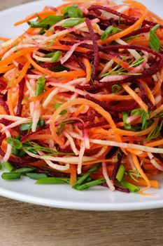 plate salad of shredded raw beets, and carrots  on celery root  close-up