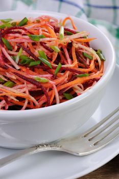 a bowl salad of shredded raw beets, and carrots  on celery root