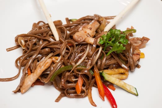 buckwheat noodles with vegetables and sticks on white background