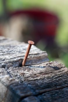 One old rusty nail in wooden log on colorful background