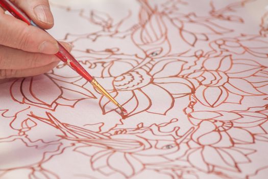 A woman hand with pencil is drawing picture with flowers