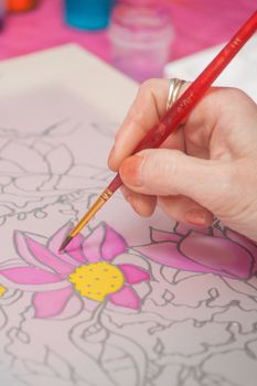 A woman hand with pencil is drawing picture with flowers