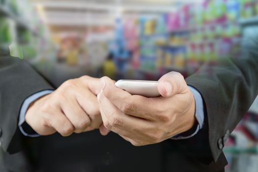 Businessman touch smart phone in hand with blur background of shopping mall market