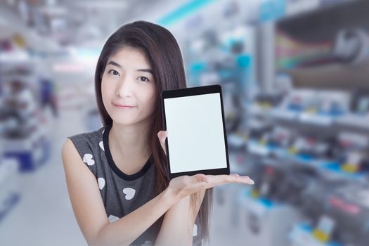 Young Asian woman show or display tablet with blank screen on shopping mall background