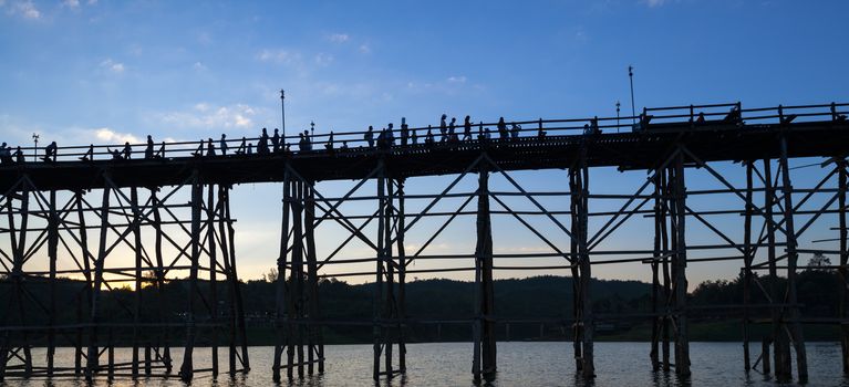silhouette of Utamanusorn Bridge (Mon Bridge), made from wooden for across the river in Sangkhlaburi District, Kanchanaburi Thailand and blue sky