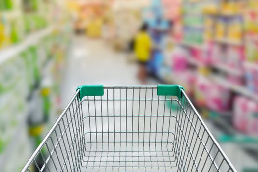 rear view of empty shopping cart with shopping mall or grocery background