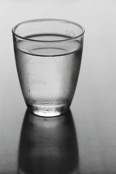 Glass of water on a reflective table top