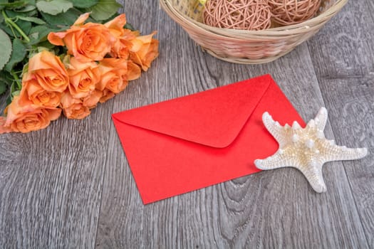 Envelope, white starfish and roses on a wooden background