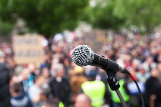 Microphone in focus against blurred crowd. Political rally.